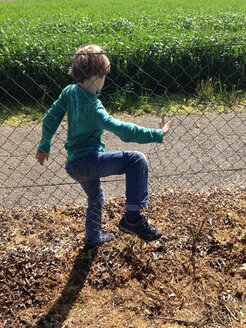 Austria, Burgenland, climbs through a hole in a fence - TKF000363