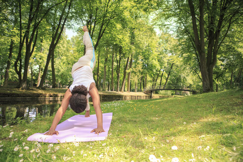 Deutschland, Frau übt Yoga in einem Park, Hundestellung - VTF000277