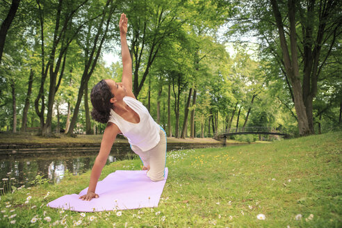 Deutschland, Frau übt Yoga in einem Park, Dreieckspose - VTF000280