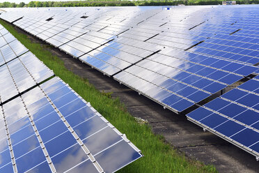 Germany, photoelectric cells of solar power plant with reflections of clouds, partial view - LYF000057