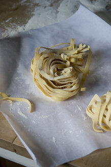 Frische ungekochte Tagliatelle und Mehl auf Backpapier - ASF005419