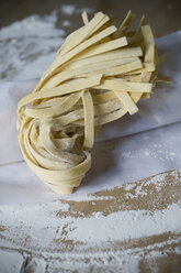 Frische ungekochte Tagliatelle und Mehl auf Backpapier - ASF005420