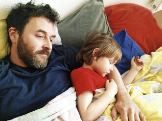 Sohn schläft im Arm seines Vaters im Bett, Berlin, Deutschland - ZMF000306