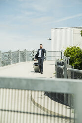 Business man on the move with rolling suitcase - UUF000877