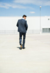 Business man walking on parking level, back view - UUF000914