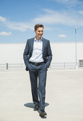 Smiling business man walking on parking level - UUF001004