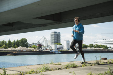 Man with headphones jogging at riverside - UUF000917