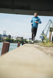 Man with headphones jogging at riverside - UUF000918