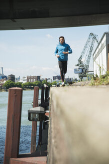 Mann mit Kopfhörern beim Joggen am Flussufer - UUF000919