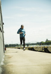 Man with headphones jogging at riverside - UUF000921