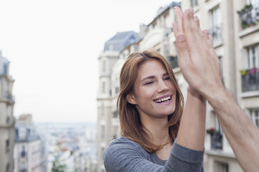 Frankreich, Paris, Porträt einer lächelnden jungen Frau, die ihrem Freund ein High Five gibt - FMKF001270