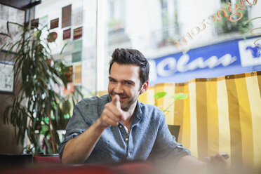 Frankreich, Paris, Porträt eines lächelnden Mannes, der in einem Cafe sitzt - FMKF001276