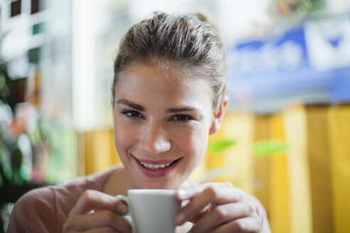 France, Paris, portrait of young woman drinking cup of coffee in a cafe - FMKF001285