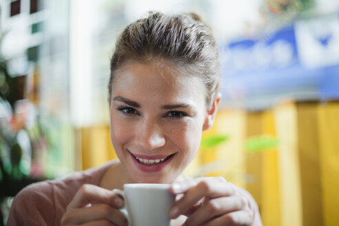Frankreich, Paris, Porträt einer jungen Frau, die in einem Café eine Tasse Kaffee trinkt - FMKF001285