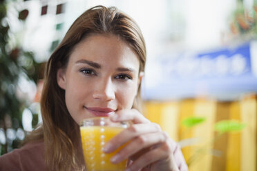 France, Paris, portrait of young woman drinking a glass of juice in a cafe - FMKF001286