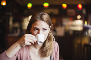 Frankreich, Paris, Porträt einer jungen Frau, die in einem Café eine Tasse Kaffee trinkt - FMKF001288