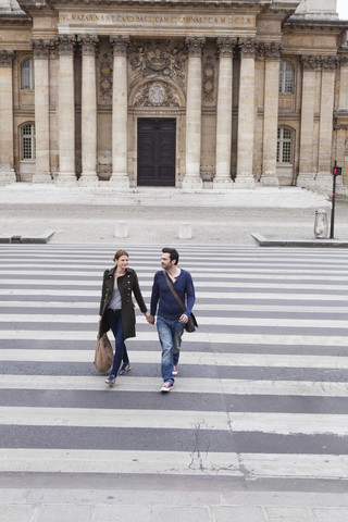 Frankreich, Paris, Paar geht Hand in Hand über den Zebrastreifen, lizenzfreies Stockfoto