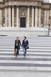 Frankreich, Paris, Paar geht Hand in Hand über den Zebrastreifen - FMKF001311