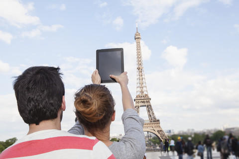 France, Paris, couple photographing Eiffel Tower with tablet computer, back view stock photo