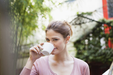 France, Paris, portrait of young woman drinking cup of coffee in a cafe - FMKF001316