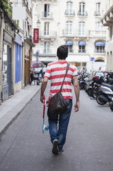 Frankreich, Paris, Mann mit Skateboard läuft auf einer Straße - FMKF001324