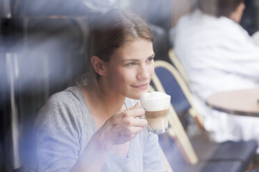 France, Paris, portrait of young woman drinking milk coffee in a cafe - FMKF001326