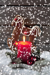 Lebkuchenpferd, brennende rote Kerze und Weihnachtsblasen mit plätscherndem Kunstschnee im Vordergrund - CSF021677