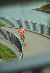 Junge Frau joggt auf einer Brücke - UUF000949