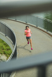 Junge Frau joggt auf einer Brücke - UUF000951