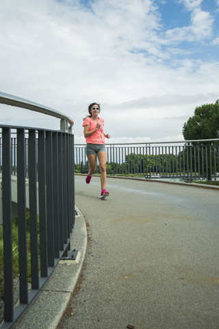 Junge Frau joggt auf einer Brücke, lizenzfreies Stockfoto