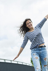 Portrait of smiling young woman balancing - UUF000964