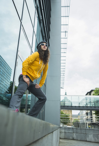 Junge Frau im gelben Trainingsanzug macht Dehnungsübungen, lizenzfreies Stockfoto