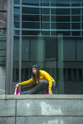 Young woman wearing yellow tracksuit top making stretching exercises - UUF000979