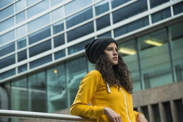 Portrait of young woman wearing yellow tracksuit top and wool cap - UUF000982