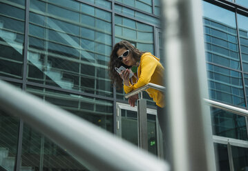 Young woman wearing yellow tracksuit top using smartphone - UUF000987