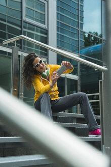 Junge Frau im gelben Trainingsanzug, die sich mit ihrem Smartphone fotografiert - UUF000990