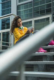 Junge Frau im gelben Trainingsanzug mit Smartphone - UUF000991