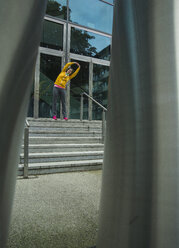 Young woman wearing yellow tracksuit top making stretching exercises - UUF000994