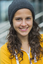 Porträt einer lächelnden jungen Frau mit gelbem Trainingsanzug und Wollmütze - UUF001002