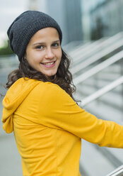 Portrait of smiling young woman wearing yellow tracksuit top and wool cap - UUF001003