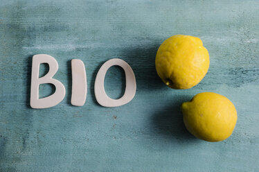 The word bio and two lemons on coloured wood, elevated view - ODF000709