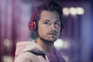 Portrait of young man with headphones listening music at night - RBF001801