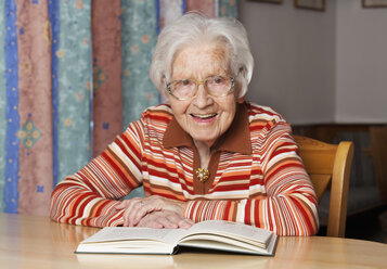 Porträt einer lächelnden älteren Frau mit geöffnetem Buch - WWF003335