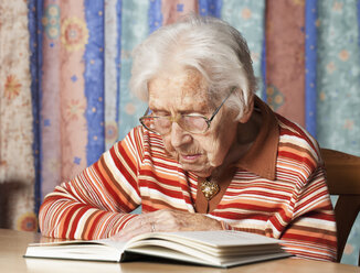 Portrait of senior woman reading a book - WWF003337