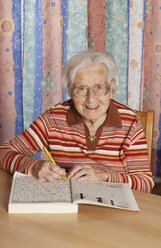 Porträt einer älteren Frau mit Kreuzworträtsel - WWF003339