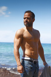 Greece, Ionic Islands, Corfu, shirtless man enjoying sunlight in front of the sea - AJF000072