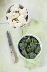 Schalen mit Brokkoli und Blumenkohlröschen, Küchenmesser und Tuch auf Holz - EVGF000695