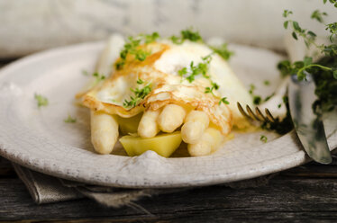 Plate of prepared white asparagus with potatoes, fried egg and herbs on wood - ODF000746