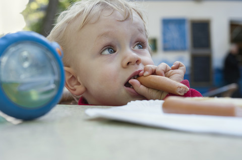 Kleiner Junge isst eine Wurst, lizenzfreies Stockfoto