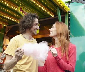 Glückliches junges Paar auf einem Jahrmarkt mit Zuckerwatte - RHF000360